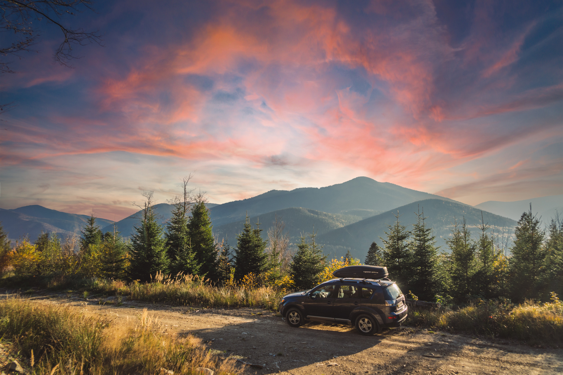 Car Driving Across Mountain Road SUV driving across a mountain road with pine trees