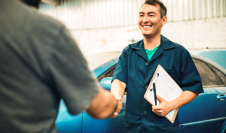 Mechanic shaking hands with happy customer after car repair, backed by Onust coverage